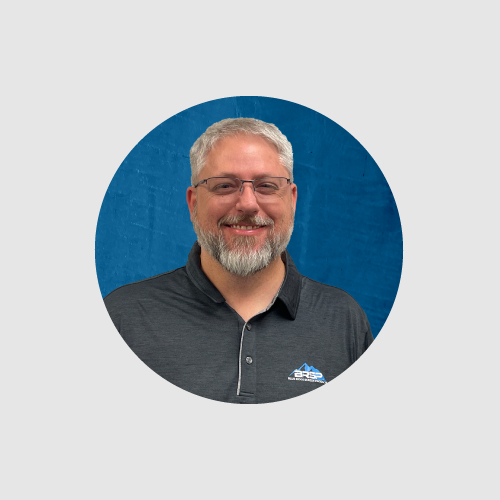 Man wearing a gray polo shirt with a logo on a blue and gray background